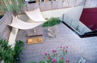 Roof garden with timber decking, awning, deckchairs, slatted trellis, kauna rush mattress, water rill, steel container with globe artichokes