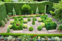 Small topiary garden enclosed by Yew hedge with Buxus central spiral, Buxus sempervirens and Buxus sempervirens variegata balls, Buxus pyramids and Bay tree. Ledge with collection of succulents, Agapanthus 'Silver Moon', Aeonium  'Sunburst', Citrus limon x 'Salicifolia'  - Pine House
