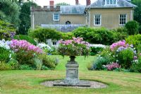 The Sickle Beds, in the formal garden to the west of the house, with central urn and beds full of Phlox, Lythrums, Crinums and other herbaceous perennials - Old Rectory, Pulham, Dorset
