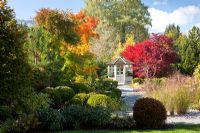 Autumn in a Bavarian garden with  a white painted wooden pavilion and groups of Buxus spheres. Plants include - Acer palmatum, Acer saccharinum, Betula pendula, Miscanthus sinensis, Pinus, Rhododendron, Taxus baccata and Wisteria
