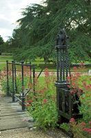 Wooden bridge with Centranthus ruber - Red Valerian and metal obelisks - Mannington Hall, Near Norfolk, UK