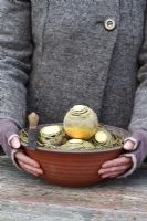 Woman holding a bowl of swedes protected with raffia