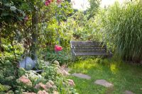Secluded seating area, plants include Rosa, Sedum 'Herbstfreude', Miscanthus sinensis - Marx Garden 
 
