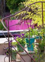 View across rusted iron railings to pool and pink, rendered wall with waterfall