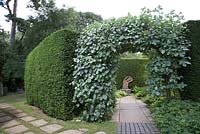 Arch with view of Simon Verity's statue 'Seated Lady' surrounded by yew hedging.