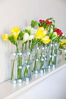 Freesias in glass vases on a mantlepiece