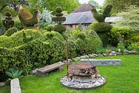 Topiary garden including Yew birds, wedding-cake tiers and crowns. Firepit atop large flint stone with kindling 