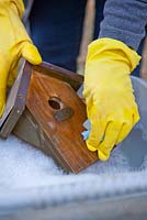 Cleaning a bird house in hot soapy water - inside and out
