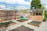 Step-by-steps - Vegetable garden overview with raised beds and greenhouse in early summer