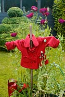 Garden scarecrow surrounded by purple Papaver somniferum - Opium Poppies and Onions