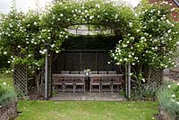 Wooden furniture in gazebo with climbing Rosa - The Flint House 
