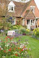 Cottage with borders containing Aquilegia, Euphorbia and Geum 'Red Wings'