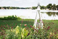 White wooden obelisks with Canna 'Bengal Tiger' - Bengal Tiger Variegated Canna Lily, Euphorbia hybrid 'Diamond Frost' and Salvia splendens 'Van Houttei' on the edge of picturesque Lake Osceola - Albin Polasek Museum 