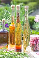 Herbal, tarragon and nasturtium vinegar on garden table 