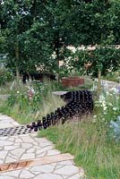 Rows of empty beer bottles snaking through wild flower garden. The badger beer garden, Hampton Court flower show 2012