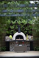 'Live Outdoors'. Hampton Court Flower Show 2012. Outdoor stove and seating area with vertical planting of ferns and dark heucheras.