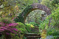 Steps and circular stone arch leading from the main garden to the vegetable garden at Greencombe Gardens, Somerset