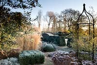 Formal garden in winter with Sedum, Calamagrostis acutiflora, clipped Box, Olea and yorkstone paths - Winfield House