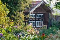 Traditional wooden bee house in a Bavarian country garden with Hemerocallis borders