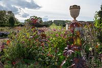 Centre circular bed in the rose garden with urn surrounded by a mass of flowers including amaranthus, dahlias, salvias and ricinus