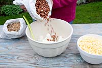 Step by step for creating hanging bird feeders out of teacups and yoghurt pots - adding peanuts 