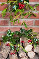 Logs by the fireside with Christmas decorations of mistletoe, holly and rose hips