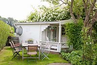 Summerhouse with table and chairs. Rosa 'Bobbie James'