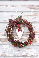 Snowy wreath decorated with Gaulteria procumbens berries and heart with ribbon