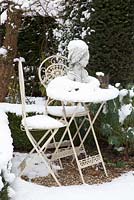 Statue on table covered in snow with Taxus and Euphorbia planting