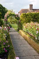 View of house from The English Rose Garden leading to archway with Rosa 'Madame Isaac Pereire', Rosa 'Brother Cadfael', 'Falstaff', 'Rose de Rescht', 'The Countryman', 'Erfurt' - Town Place