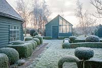 View to garden store and lean to greenhouse. Yew and box topiary and dwarf hedges on frosty morning in December - The Mill House, Little Sampford, Essex
