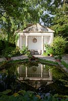 The classical summerhouse and pond at Barnsley House Garden in Gloucestershire