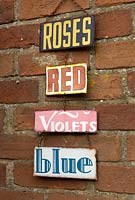 Decorative garden signs hanging on brick wall