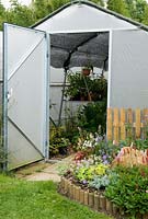 Specialised 'Haygrove' polytunnel with fleece lined roof and hanging shelves - Furze House NGS, Rushall, Norfolk