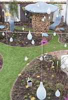 Modern garden with decorative metal bird feeders suspended from wire 