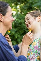 Mother and daughter playing with Ranunculus repens - Creeping Buttercup