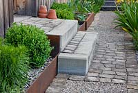 Corten steel edged plant troughs and steps made of concrete and granite, paving accentuates house entrance