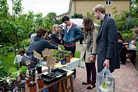 Young people buying plants from stall at King Henry's Walk Garden, urban community allotments, London Borough of Islington, UK