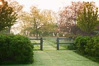 Lines of Rosa rugosa lead to a gate in the fence between formal and natural gardens. 