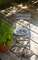 Childs chair with plate of pebbles on wooden decking patio