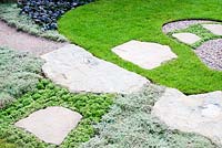 Paths of stone and gravel with adjacent lawn and planting of Ajuga reptans ' Black Scallop' Thymus pseudolanuginosus and Saxifraga paniculata 'Correvoniana' in 'Reflections of Japan'.  Gold medal winner at RHS Tatton Flower Show 2013