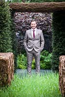 As Nature Intended Garden, Silver gilt medal winner, Chelsea Flower Show 2013. Jamie Dunstan standing between woven willow sculptures and yew hedging.
