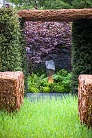 As Nature Intended Garden, Silver gilt medal winner, Chelsea Flower Show 2013. View through yew hedging to stone landscaped floor and border planted with ferns and Polygonatum with drystone wall and stone sculpture