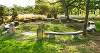A circle of wooden benches by Marc Nucera in woodland with Stipa tenuissima. Provence, France, Domaine de la Verriere