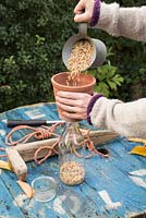 Using terracotta pot to pour in bird feed.