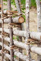 Fence made from tree trunks braided with bark.