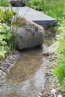 Fresh stream flowing beneath a bridge, along a pebble lined basin. Fresh Garden: Cloudy Bay Discovery Garden. 