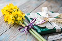 Valentine gift decorated with heart shape cut-outs from a book and a bouquet of Daffodils. Narcissus