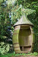Decorative revolving barrel seat under yew tree - Farleigh House, Hampshire