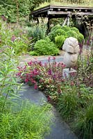 Contemporary garden with statue. Planting includes Amsonia hubrichtii, Asclepias incarnata, Sedum 'Red Cauli'